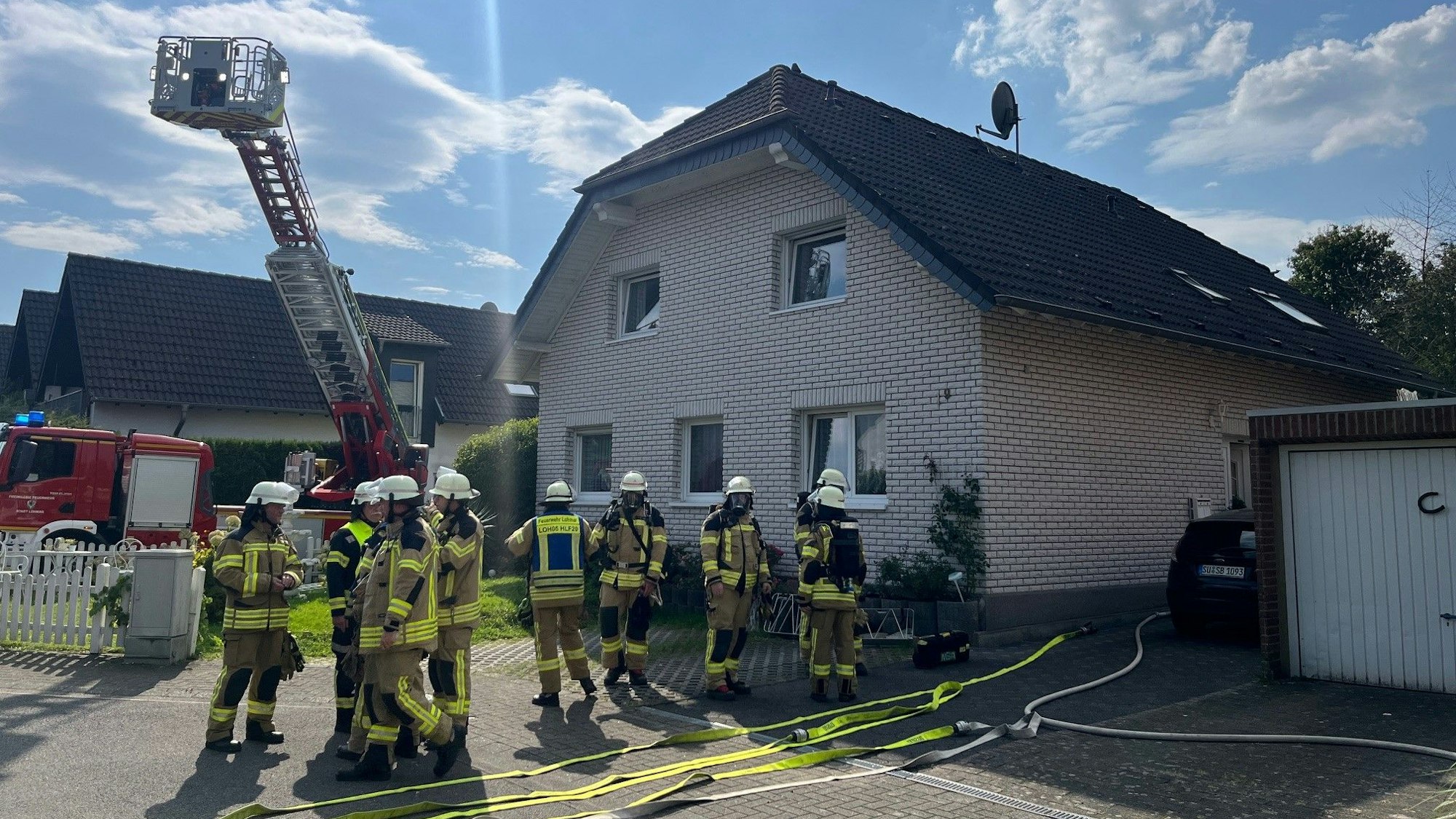 Feuerwehrleute und eine Drehleiter stehen vor einem Haus.