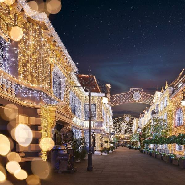 Eine Straße; die Fassaden der Häuser an beiden Seiten sind voller Lichter.