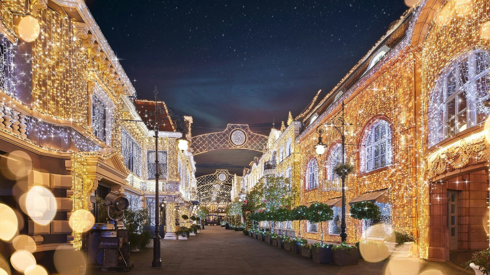 Eine Straße; die Fassaden der Häuser an beiden Seiten sind voller Lichter.