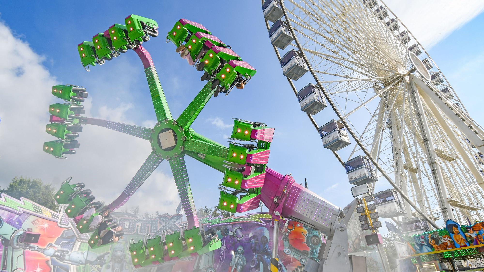 Pützchens Markt. Zu sehen: Ein Fahrgeschäft und ein Riesenrad.