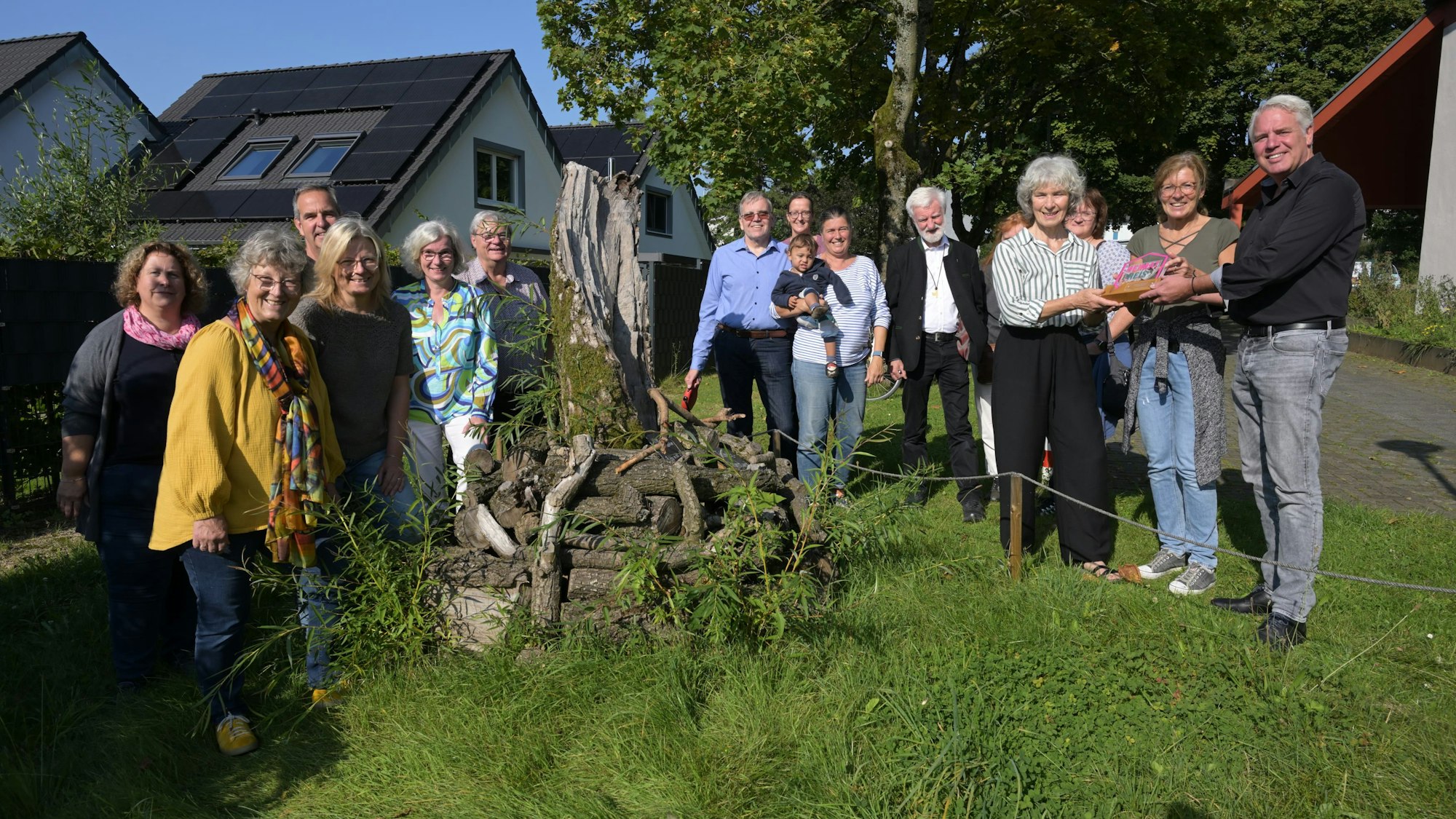 Eine Gruppe von Menschen stehen um einen Haufen Totholz herum.