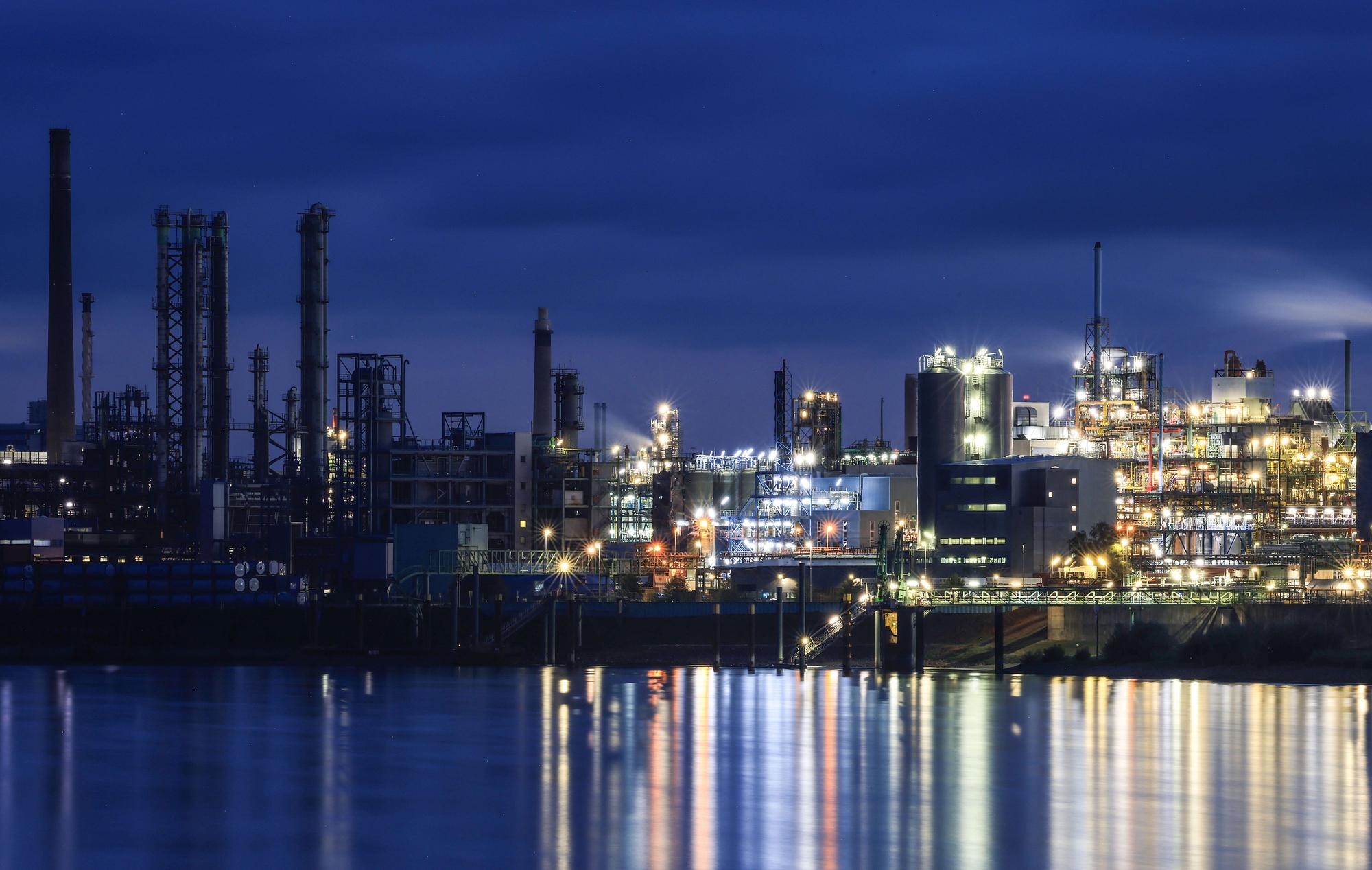 Lichter von Werksanlagen auf dem Chempark in Leverkusen spiegeln sich im Rhein.
