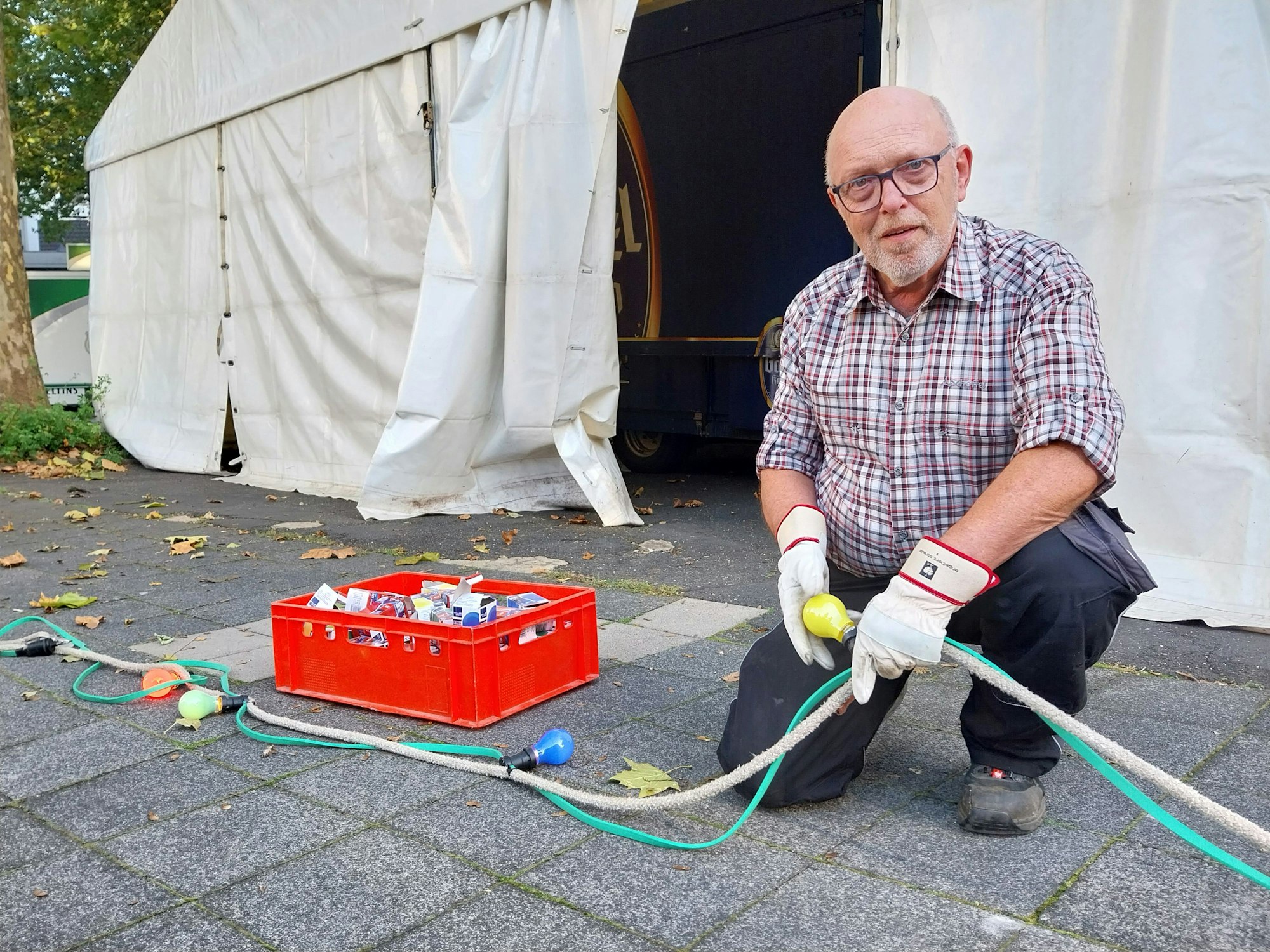Ein Mann kniet vor einer Lichterkette.
