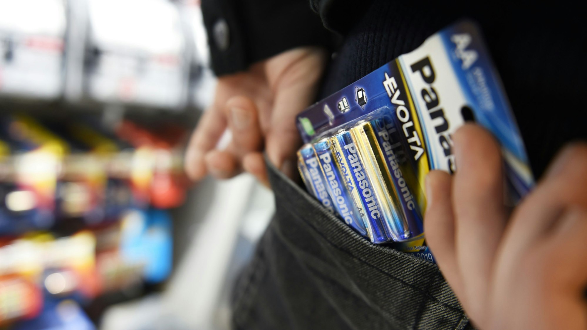 Das Bild zeigt eine Person, die eine Packung mit Batterien in die Hosentasche steckt.