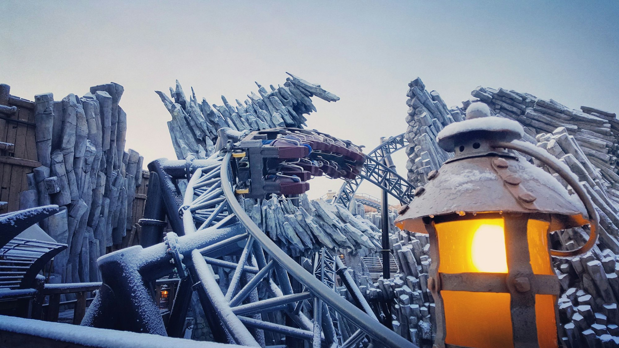 Die Achterbahn Taron im Phantasialand ist schneebedeckt. Im Vordergrund eine Laterne.