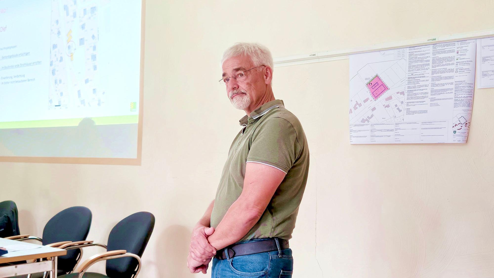 Das Bild zeigt Heinz Frey, der mit verschränkten Armen vor einer Wand steht.