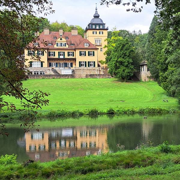 Schlosshotel Lerbach ist samt Spiegelbild im Teich der Parkanlage zu sehen.
