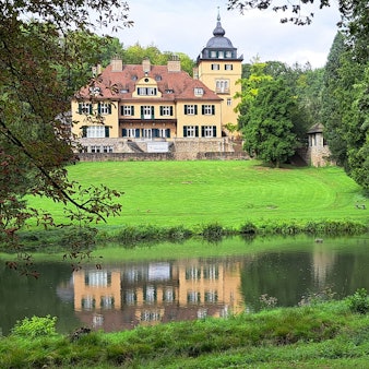 Schlosshotel Lerbach ist samt Spiegelbild im Teich der Parkanlage zu sehen.