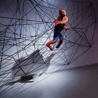 12.09.2024, Nordrhein-Westfalen, Düsseldorf: Eine Spiderman Figur aus Stoff in einem Netz ist in der Ausstellung «Superheroes» im NRW-Forum zu sehen. Die Ausstellung zeigt vom 13.09.2024 bis zum 11.05.2025 1600 Exponate, darunter Original-Zeichnungen, Medienkunstinstallationen, Skulpturen und Filmausschnitte.