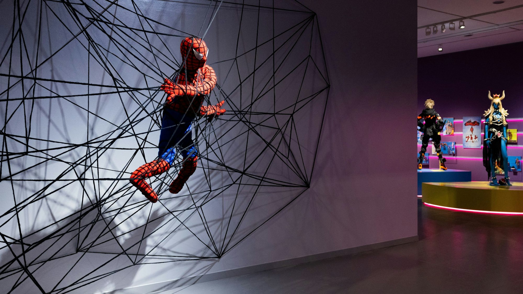 12.09.2024, Nordrhein-Westfalen, Düsseldorf: Eine Spiderman Figur aus Stoff in einem Netz ist in der Ausstellung «Superheroes» im NRW-Forum zu sehen. Die Ausstellung zeigt vom 13.09.2024 bis zum 11.05.2025 1600 Exponate, darunter Original-Zeichnungen, Medienkunstinstallationen, Skulpturen und Filmausschnitte.