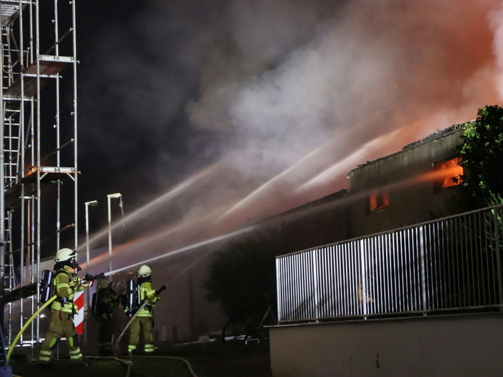 Das Bild zeigt zwei Feuerwehrleute, die einen Großbrand löschen.