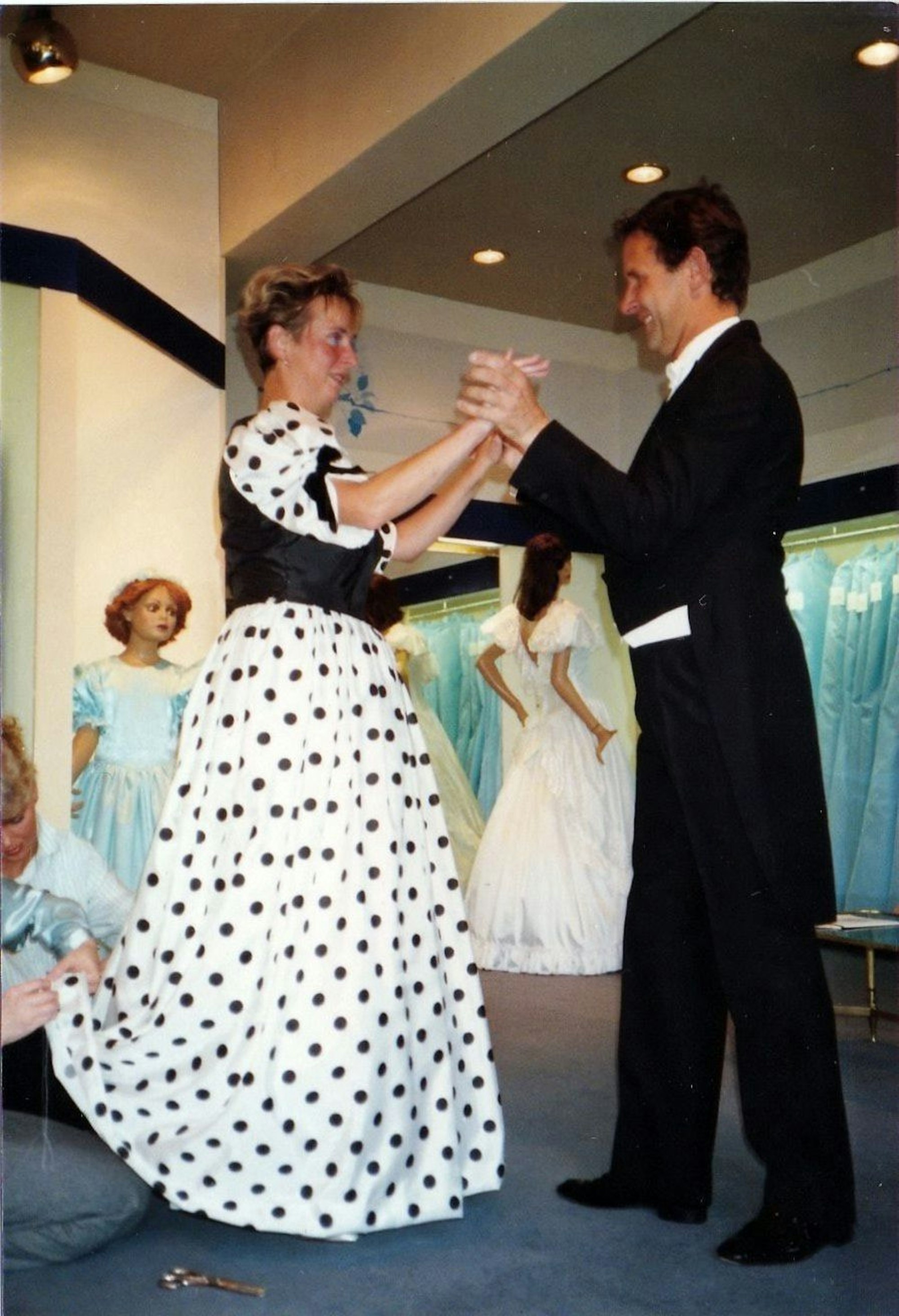 Evelyn und Hans-Georg Stallnig tanzen, sie im gepunkteten Ballkleid, er im Wrack. Eine Frau kniet hinter Evelyn, um das Kleid zu kürzen.