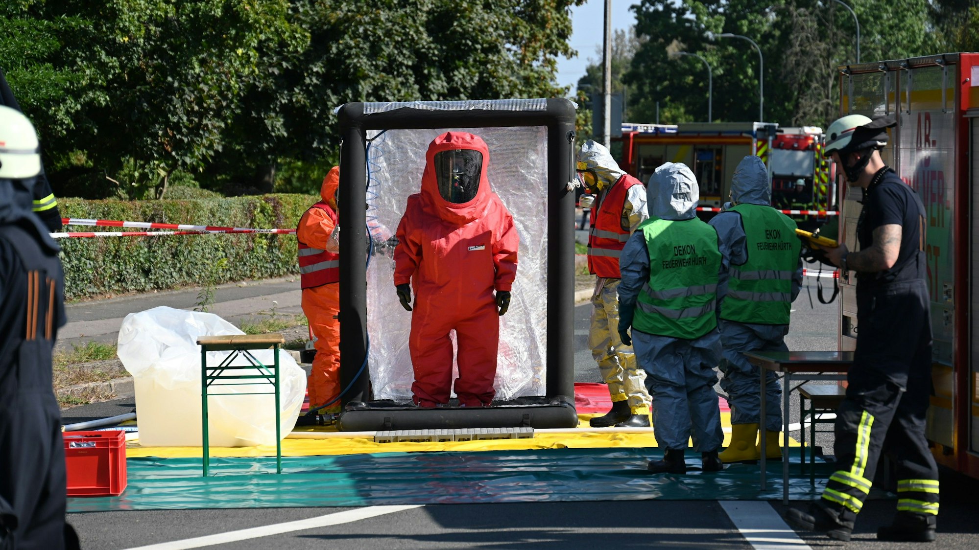 Das Bild zeigt mehrere Einsatzkräfte in Vollschutzanzügen.