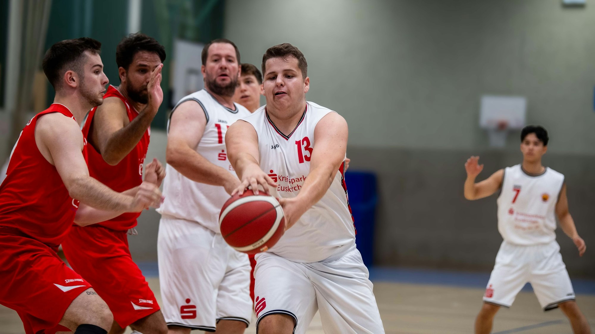 Ein Basketballspieler aus Zülpich greift während eines Testspiels nach dem Ball. Mitspieler und Gegenspieler schauen zu.