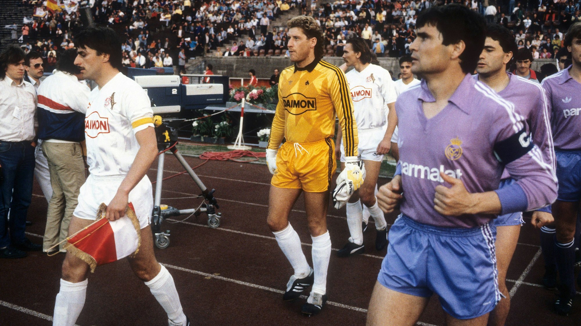 Klaus Allofs (li.) führt den 1. FC Köln am 6. Mai 1986 als Kapitän ins Berliner Olympiastadion, wo die Kölner das Final-Rückspiel im Uefa-Pokal gegen Real Madrid austrugen.