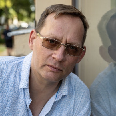 22.08.2024, Sachsen, Leipzig: Der Schriftsteller Clemens Meyer spiegelt sich in einer Fensterscheibe. In seinem neuen Roman ·Die Projektoren· nimmt Meyer auf rund 1000 Seiten seine Leserinnen und Leser mit in die deutsche und europäische - speziell jugoslawische - Vergangenheit und Gegenwart. Das ambitionierte Werk steht auf der Shortlist für den Deutschen Buchpreis.