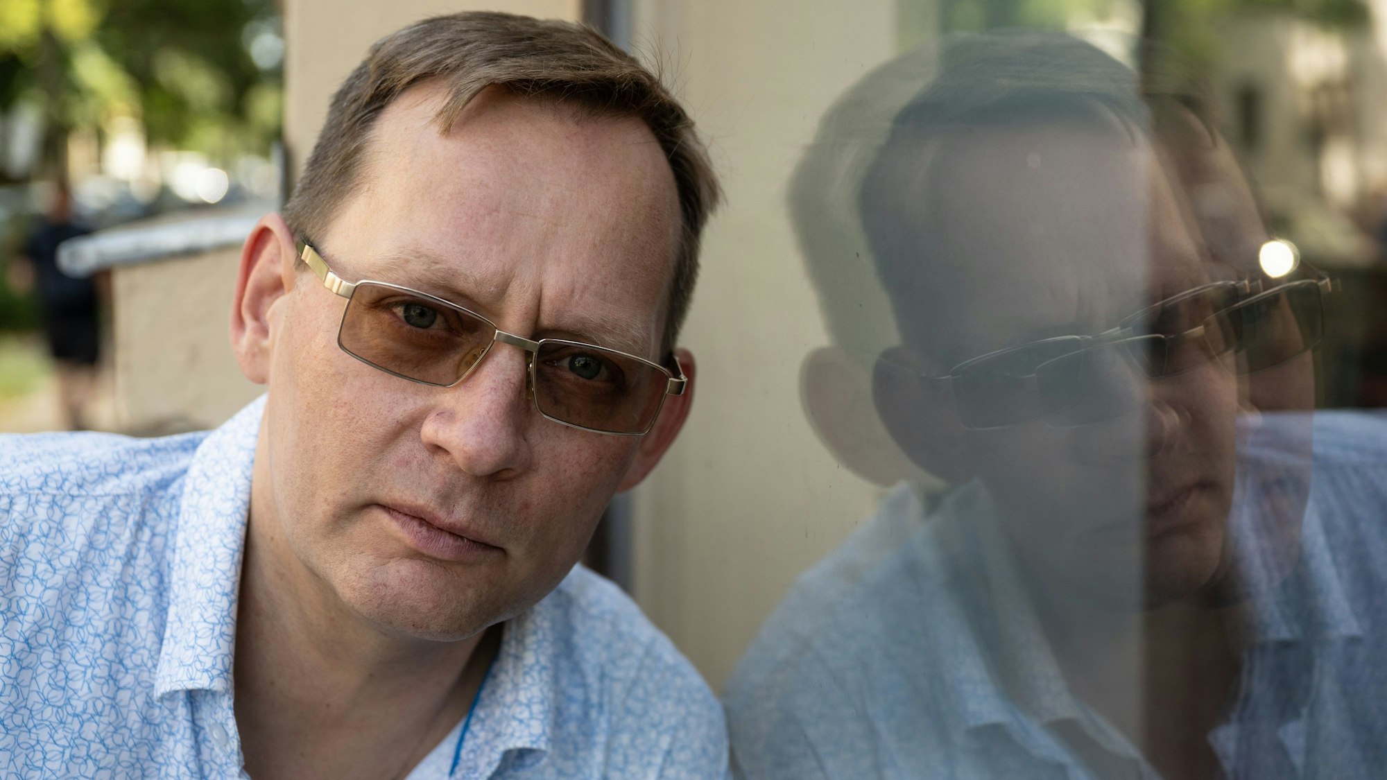 22.08.2024, Sachsen, Leipzig: Der Schriftsteller Clemens Meyer spiegelt sich in einer Fensterscheibe. In seinem neuen Roman ·Die Projektoren· nimmt Meyer auf rund 1000 Seiten seine Leserinnen und Leser mit in die deutsche und europäische - speziell jugoslawische - Vergangenheit und Gegenwart. Das ambitionierte Werk steht auf der Shortlist für den Deutschen Buchpreis.