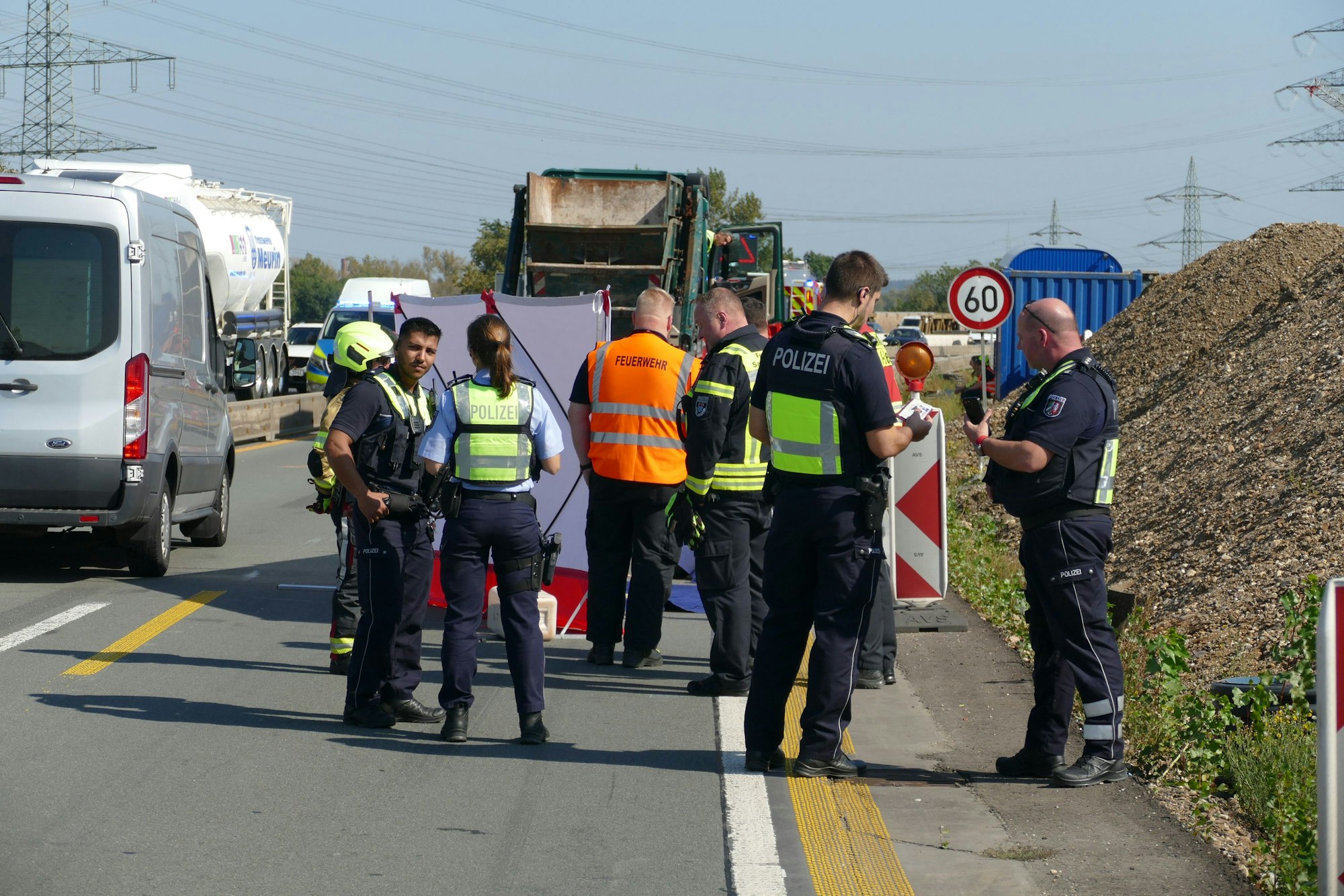 Rettungskräfte und Polizeibeamte stehen an einer Unfallstelle.