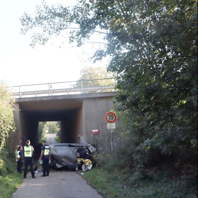 Auf dem Foto stehen Polizistinnen und Polizisten vor dem Autowrack.
