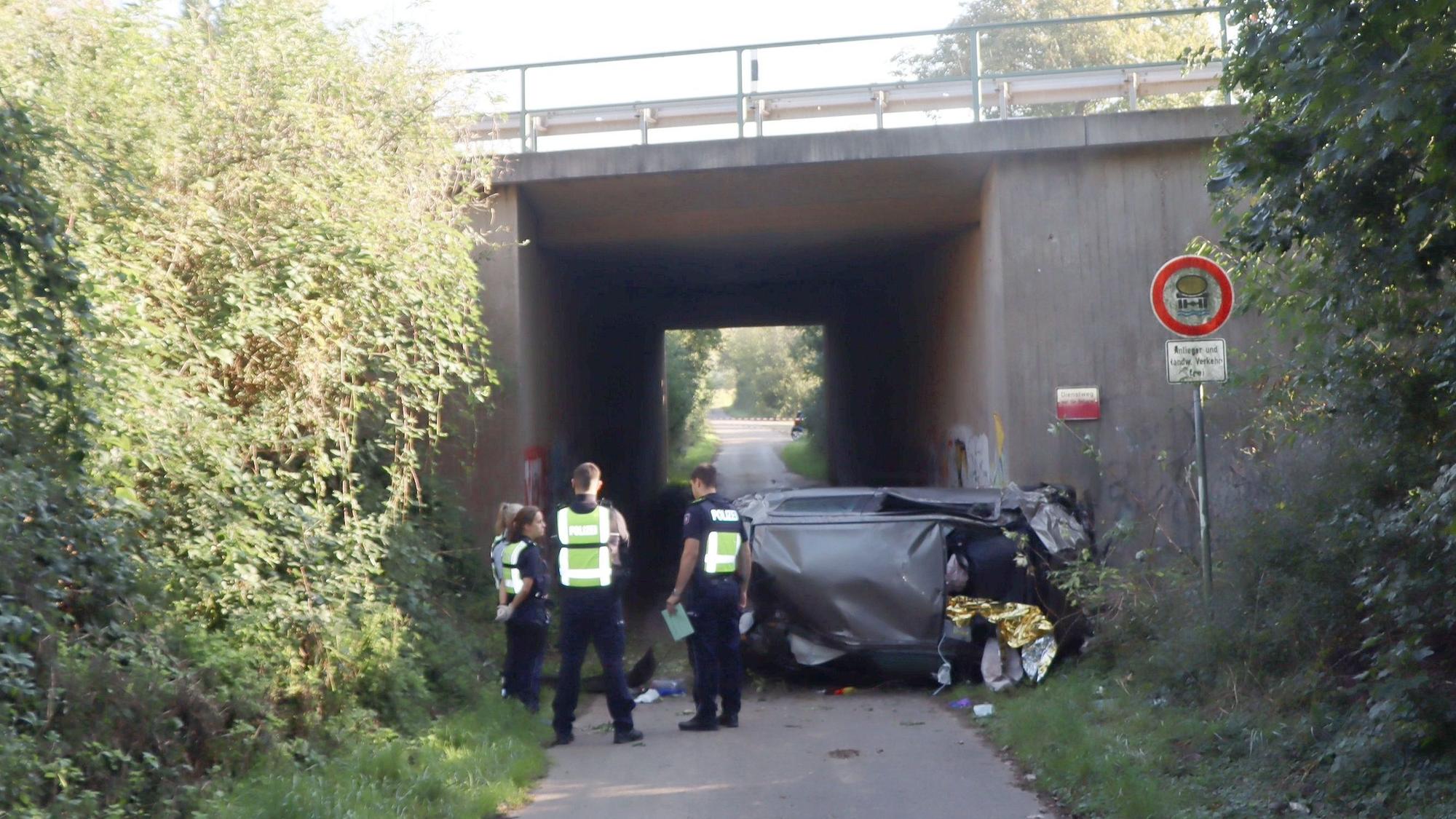 Das Bild zeigt mehrere Polizisten, die vor einem verunglückten Auto stehen.
