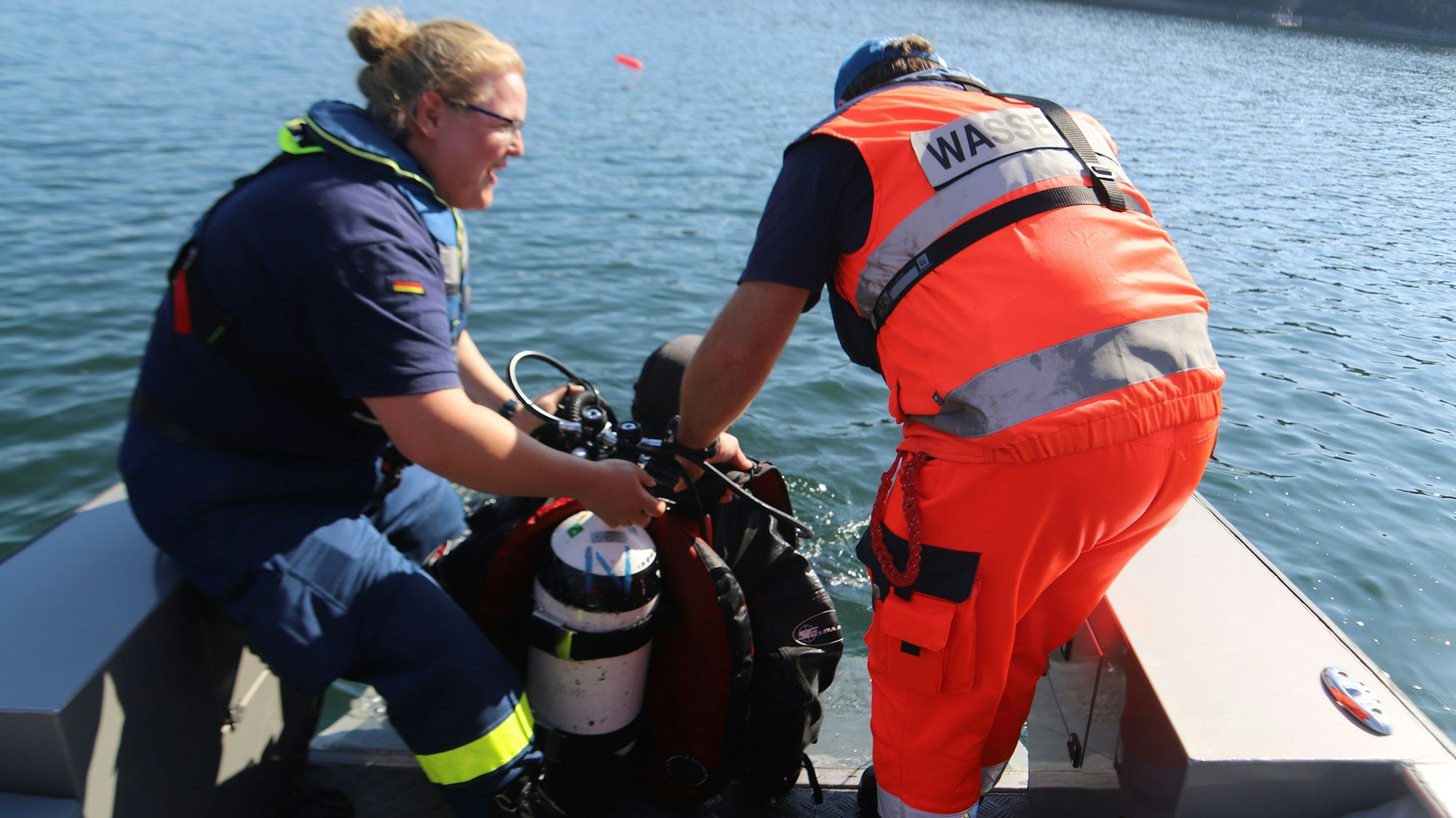 Ein Mann und eine Frau holen einen Taucher aus dem Wasser.