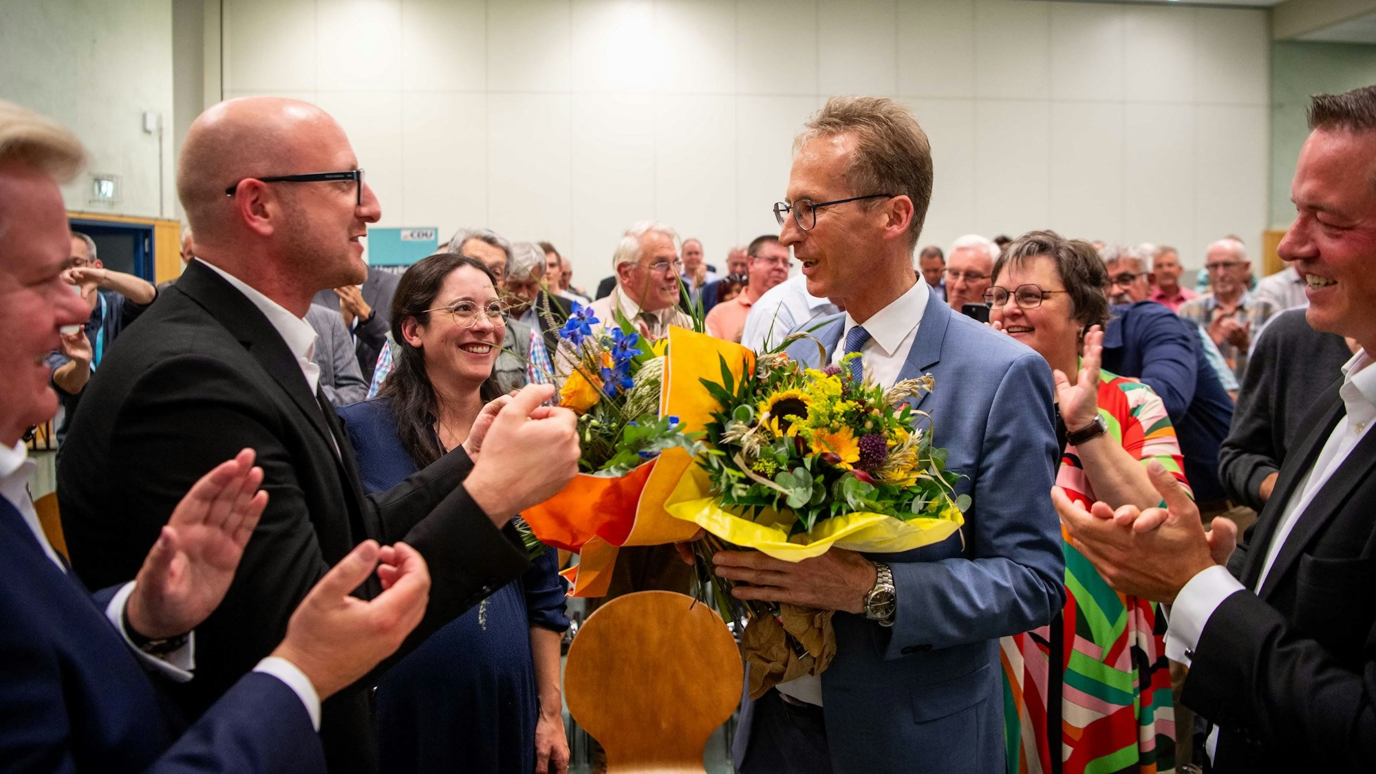 Ingo Pfennings steht neben Detlef Seif, der einen Blumenstrauß in der Hand hält.