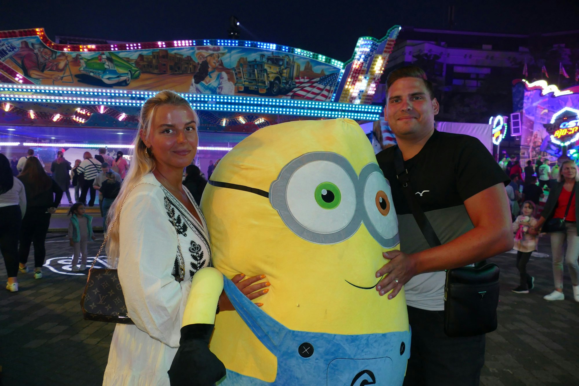 Ein Mann und eine Frau halten ein Riesen-Plüschminion fest.