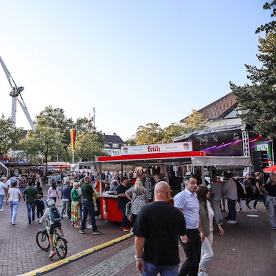 Viele Menschen befinden sich auf einem Platz und feiern ein Volksfest.