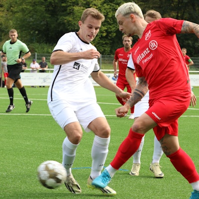 Ein Fußballspieler legt den Ball an seinem Gegner vorbei.
