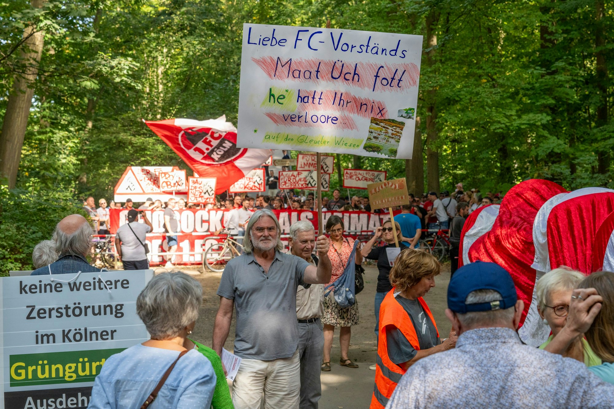 Ultras des 1. FC Köln stören eine Demonstration der Bürgerinitivate „Grüngürtel für Alle“. Diese protestiert gegen den Bau des FC-Leistungszentrums im Grüngürtel. Eine rot-weiße Raupe Nimmersatt, symbolisch für das Anfressen des Grüngürtels, besucht die Orte, die der 1. FC Köln für seine Erweiterung betrachtet.