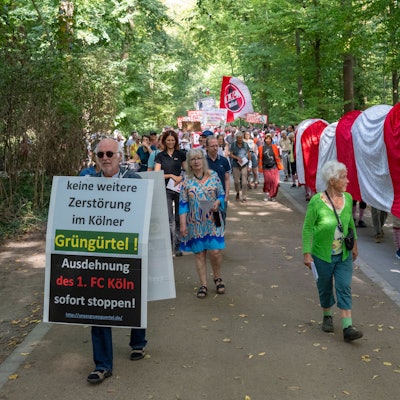 22.09.2024, Köln: Ultras des 1. FC Köln stören eine Demonstration der Bürgerinitivate „Grüngürtel für Alle“. Diese  protestiert gegen den Bau des FC-Leistungszentrums im Grüngürtel. Eine rot-weiße Raupe Nimmersatt, symbolisch für das Anfressen des Grüngürtels, besucht die Orte, die der 1. FC Köln für seine Erweiterung betrachtet.