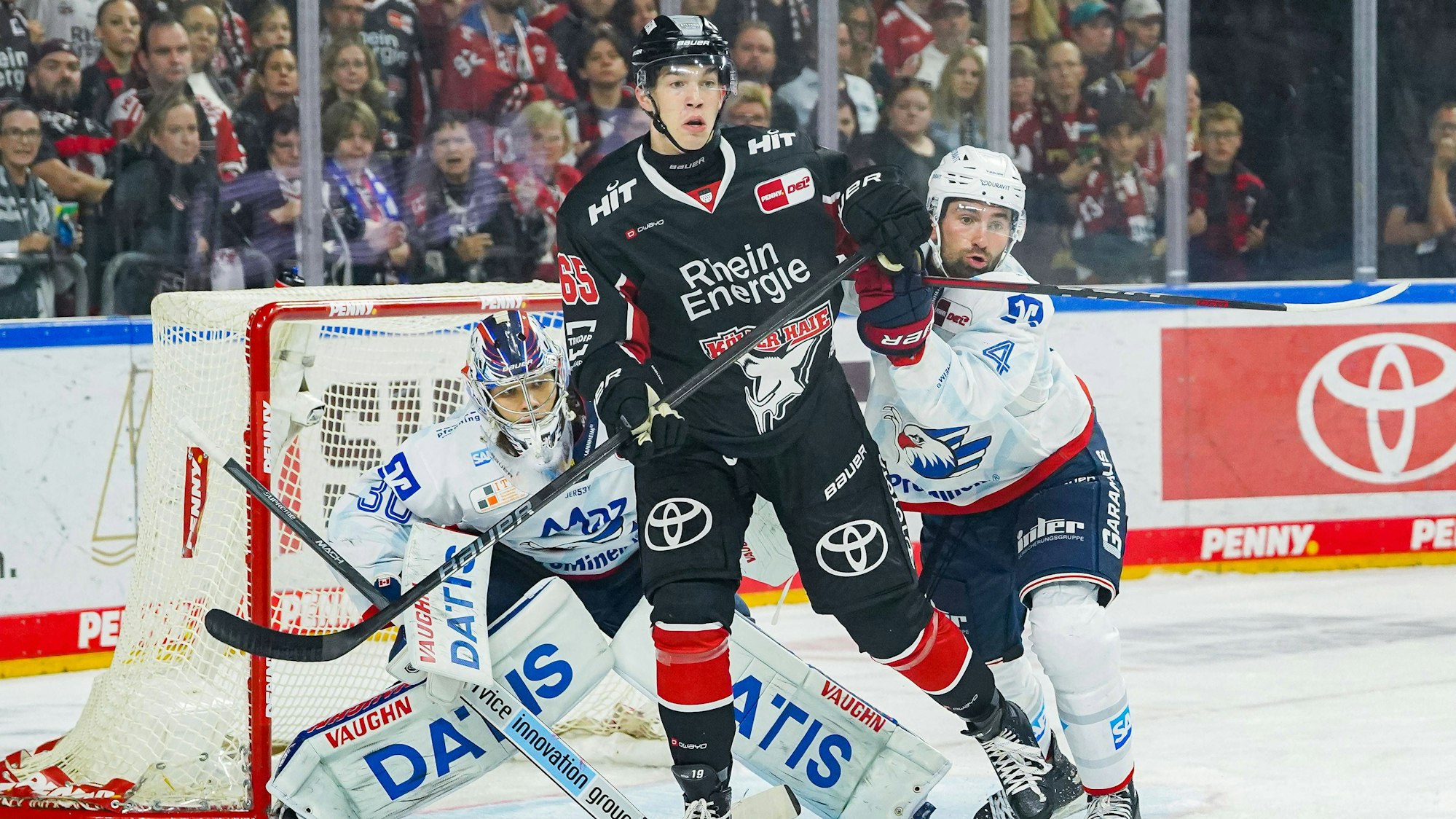 Haie-Stürmer Marco Münzenberger (M.) kämpft im Duell mit Mannheims Torwart Arno Tiefensee und Nick Cicek (r.) um den Puck.