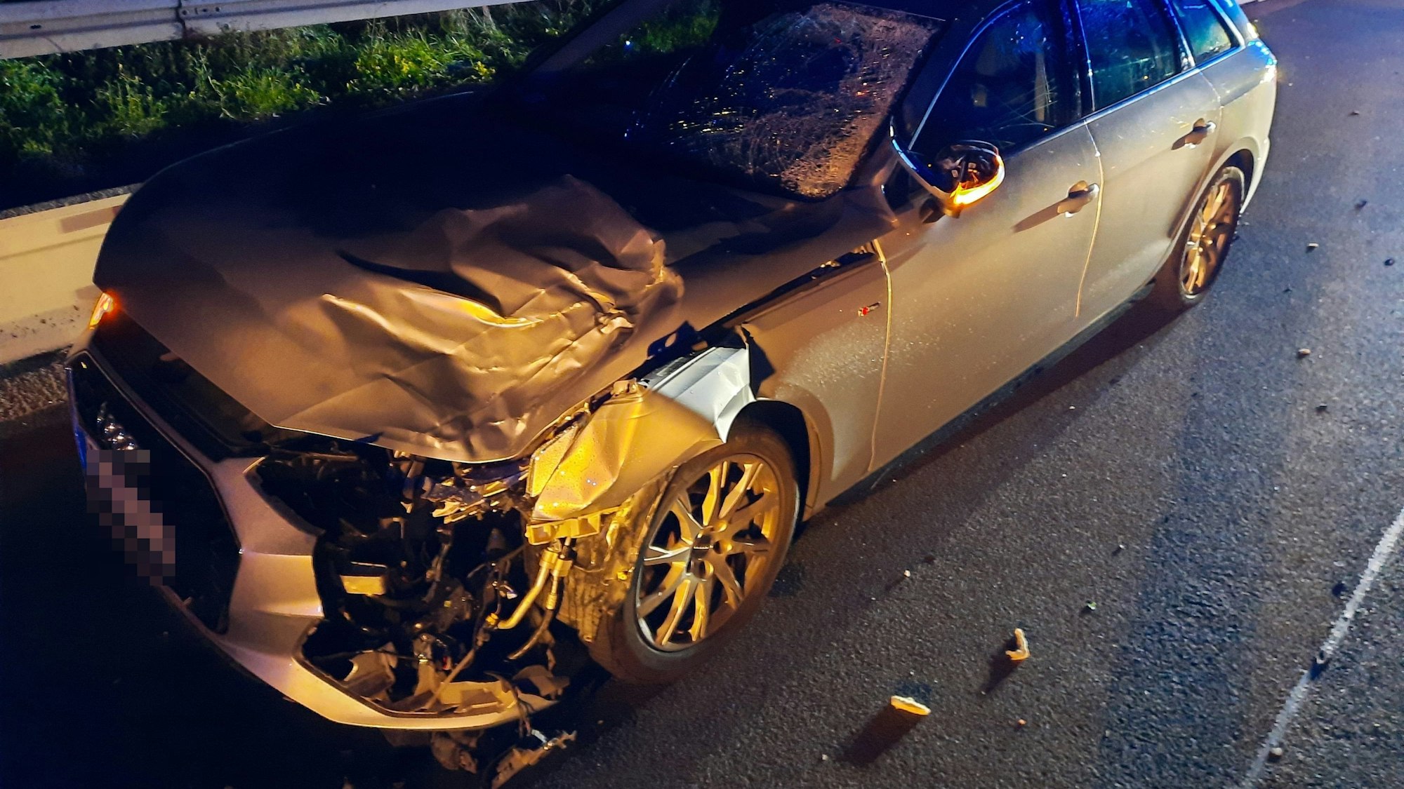 Ein Audi steht auf einer nächtlichen Fahrbahn, die Front ist zerstört, die Frontscheibe zersplittert.