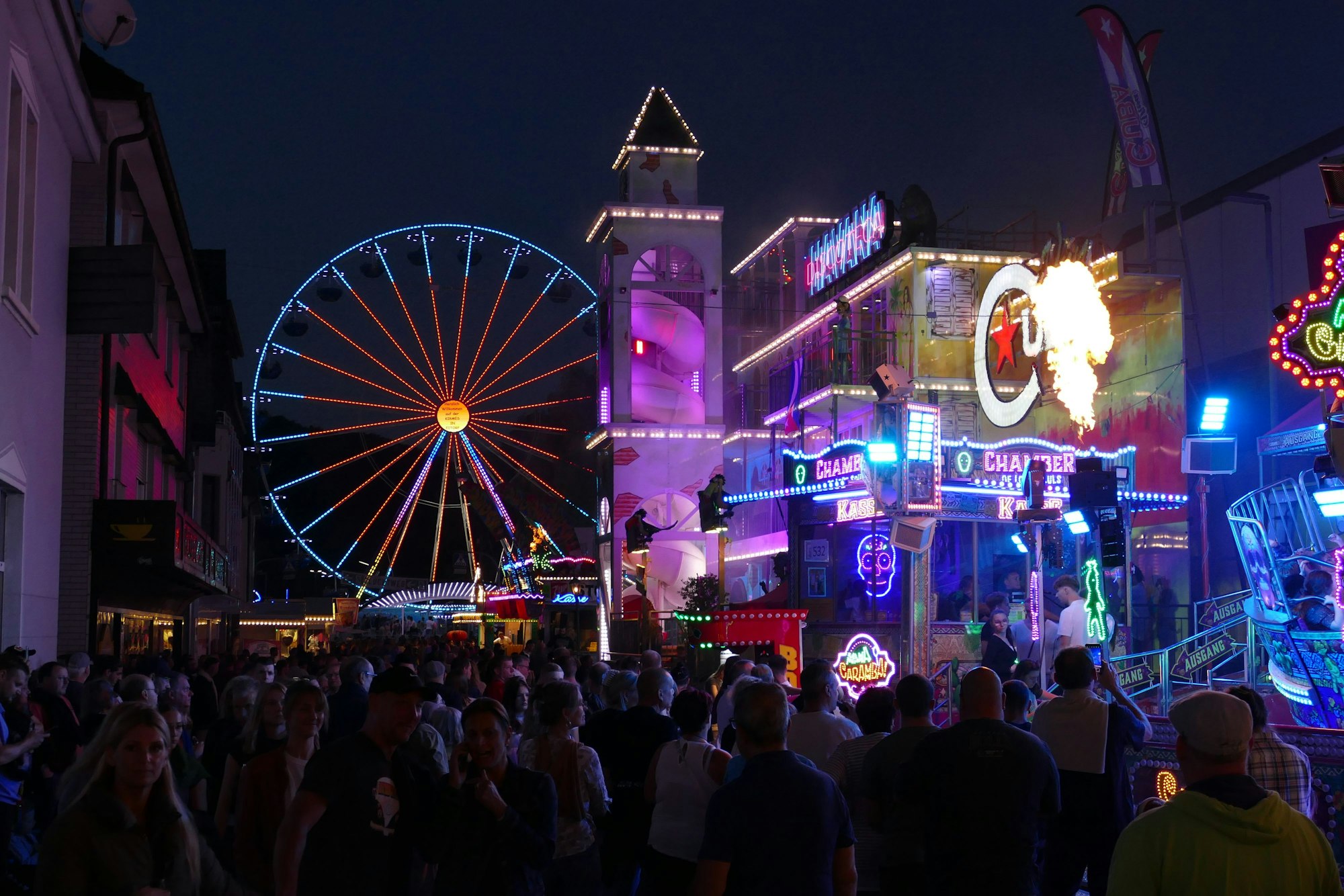 Bunt beleuchtete Fahrgeschäfte und Attraktionen an der Brückenstraße.