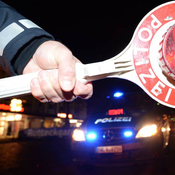 Eine Haltekelle der Polizei ist bei einer Alkoholkontrolle vor einem Polizeifahrzeug zu sehen.