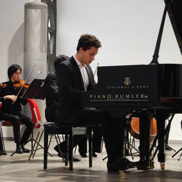 Nikola Meeuwsen am Klavier, im Hintergrund sind zwei Streicher des Folkwang Orchesters zu sehen.