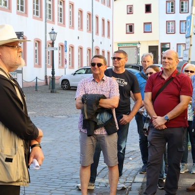 Stadthistoriker Harald Bongart trägt einen hellen Hut. Er steht auf einem Platz in Bad Münstereifel vor einer Gruppe von Männern und Frauen, die ihm zuhören.