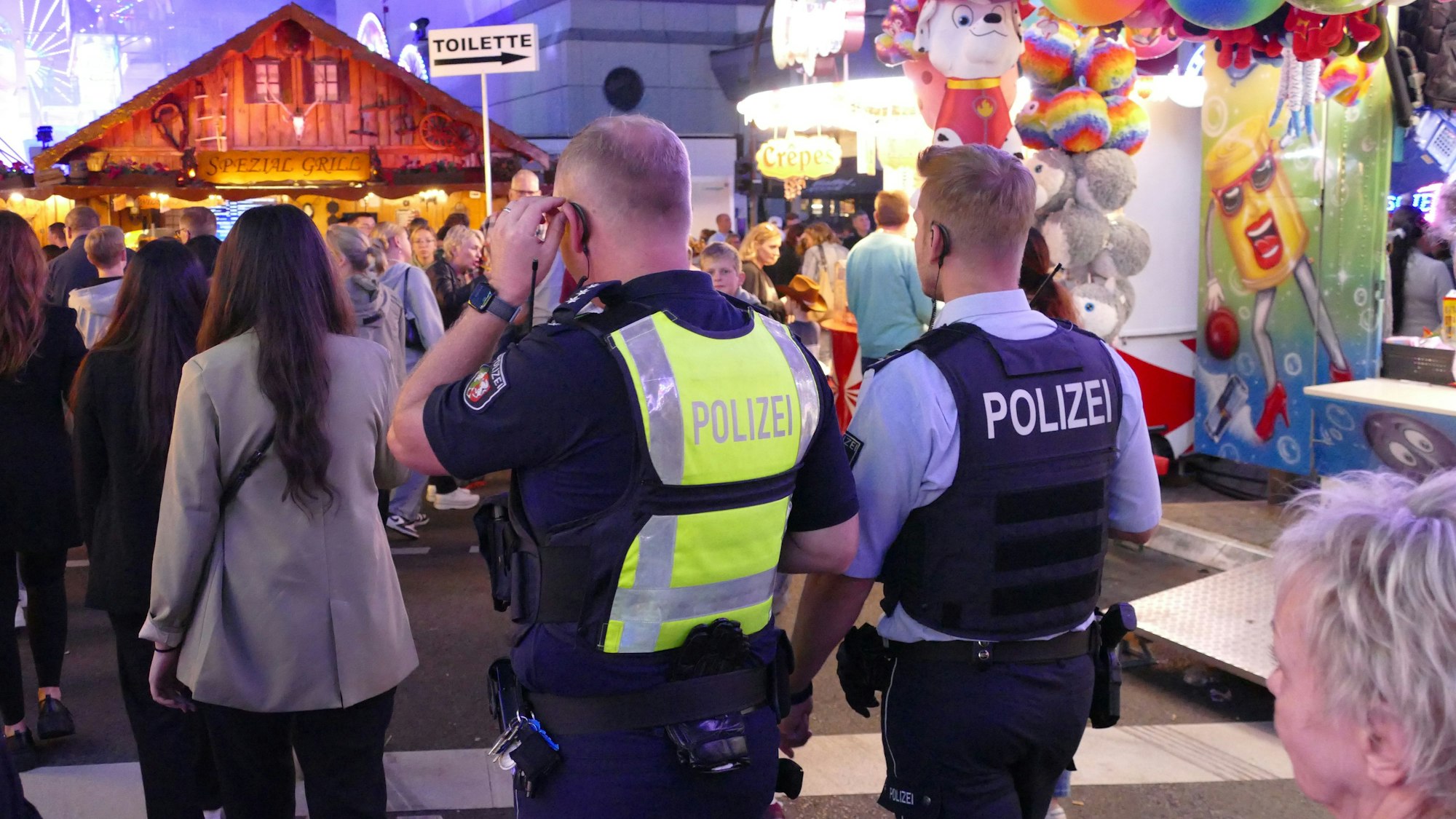 Polizisten in einer Menschenmenge auf einer Kirmes.
