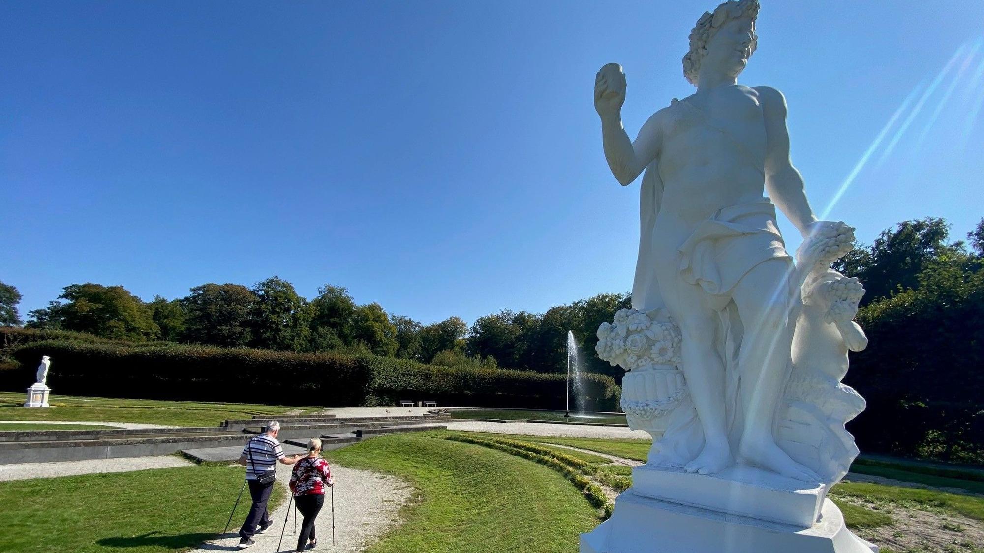 Zu sehen sind zwei Spaziergänger vor der Großen Fontäne im Schlosspark.