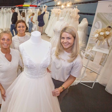 Das Foto zeigt vier Frauen an einem Stand mit Hochzeitskleidern.