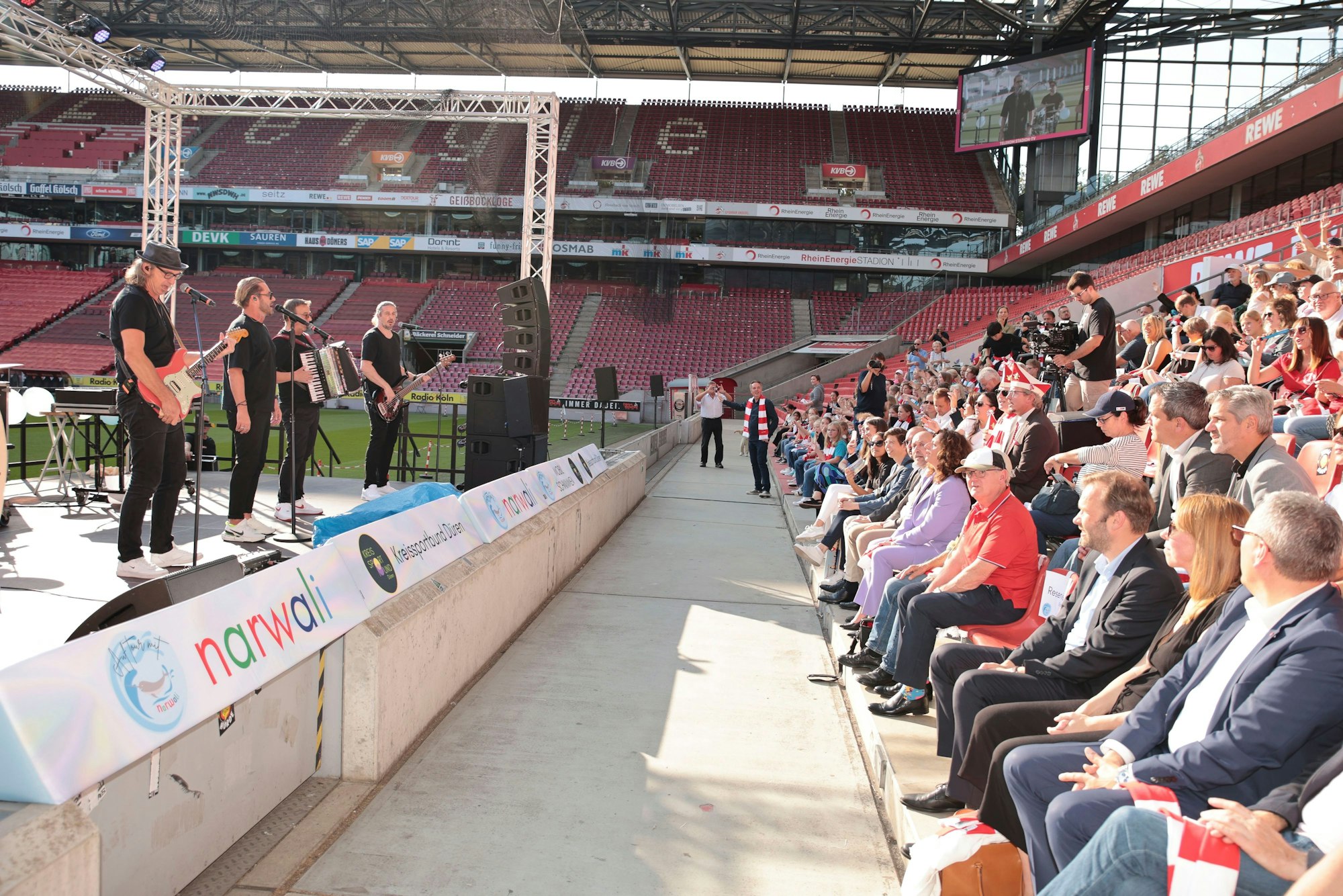 Das Bild zeigt die Band und das Publikum auf der Tribüne.