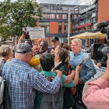 Ein Mann wird von anderen Leuten umringt und gefeiert.