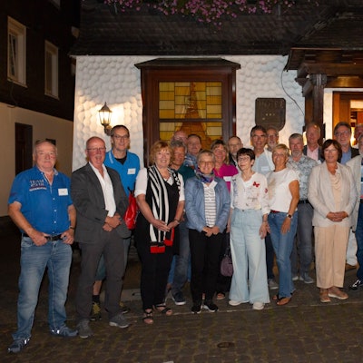 Eine Gruppe Männer und Frauen steht zum Foto aufgestellt vor dem Eingang des Restaurants Feste Neustadt.