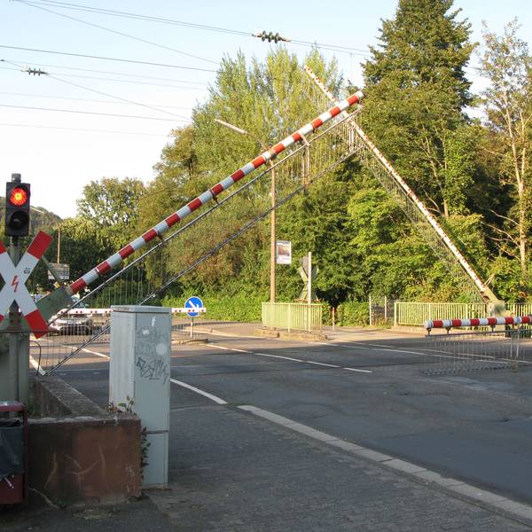 Die Schranken senken sich an einem Bahnübergang.
