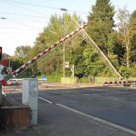 Die Schranken senken sich an einem Bahnübergang.
