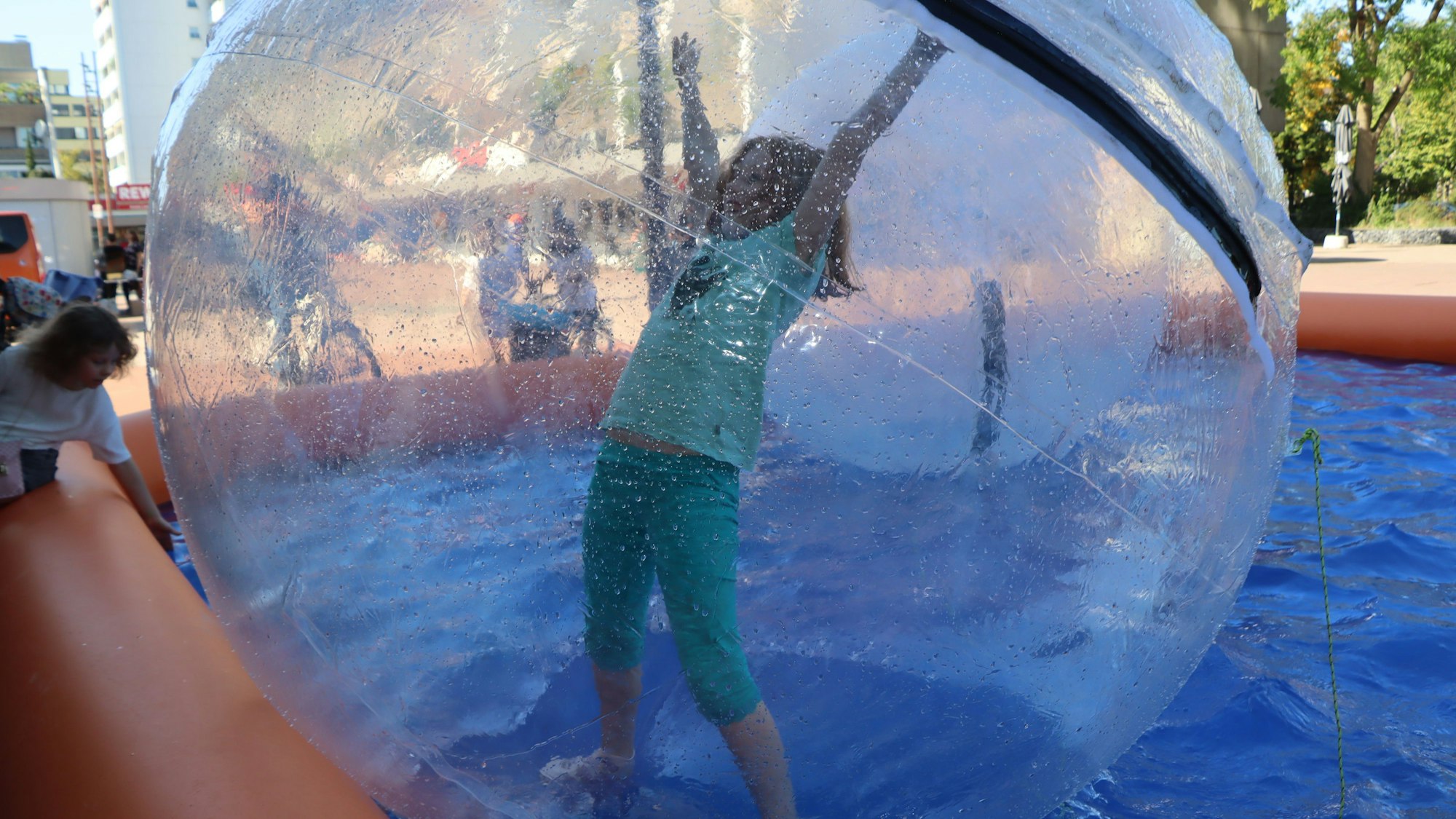 Zu sehen ist ein Mädchen in einem großen Kunststoffball.