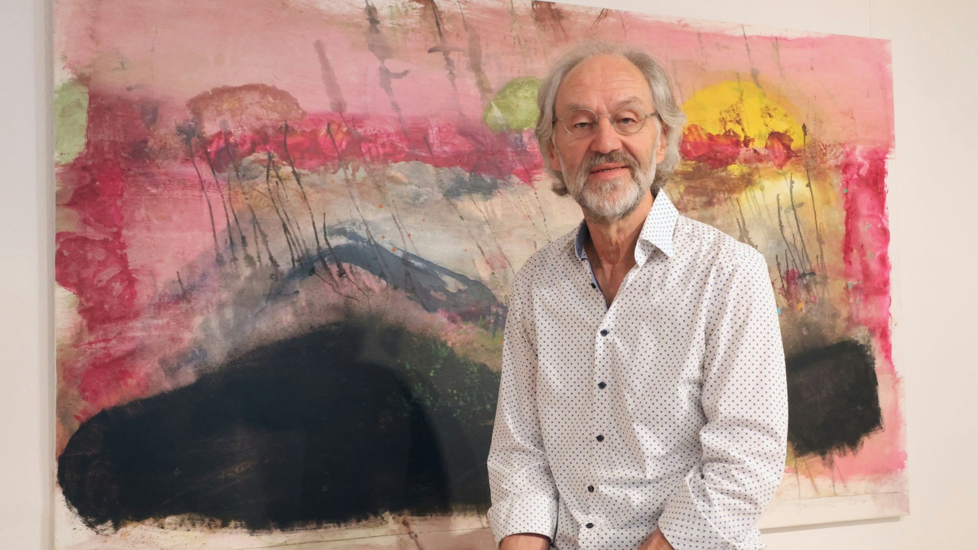 Der Künstler Bruno Obermann ist vor einem großformatigen Gemälde zu sehen, Das Bild trägt den Titel „Tod nach drei Religionen“.