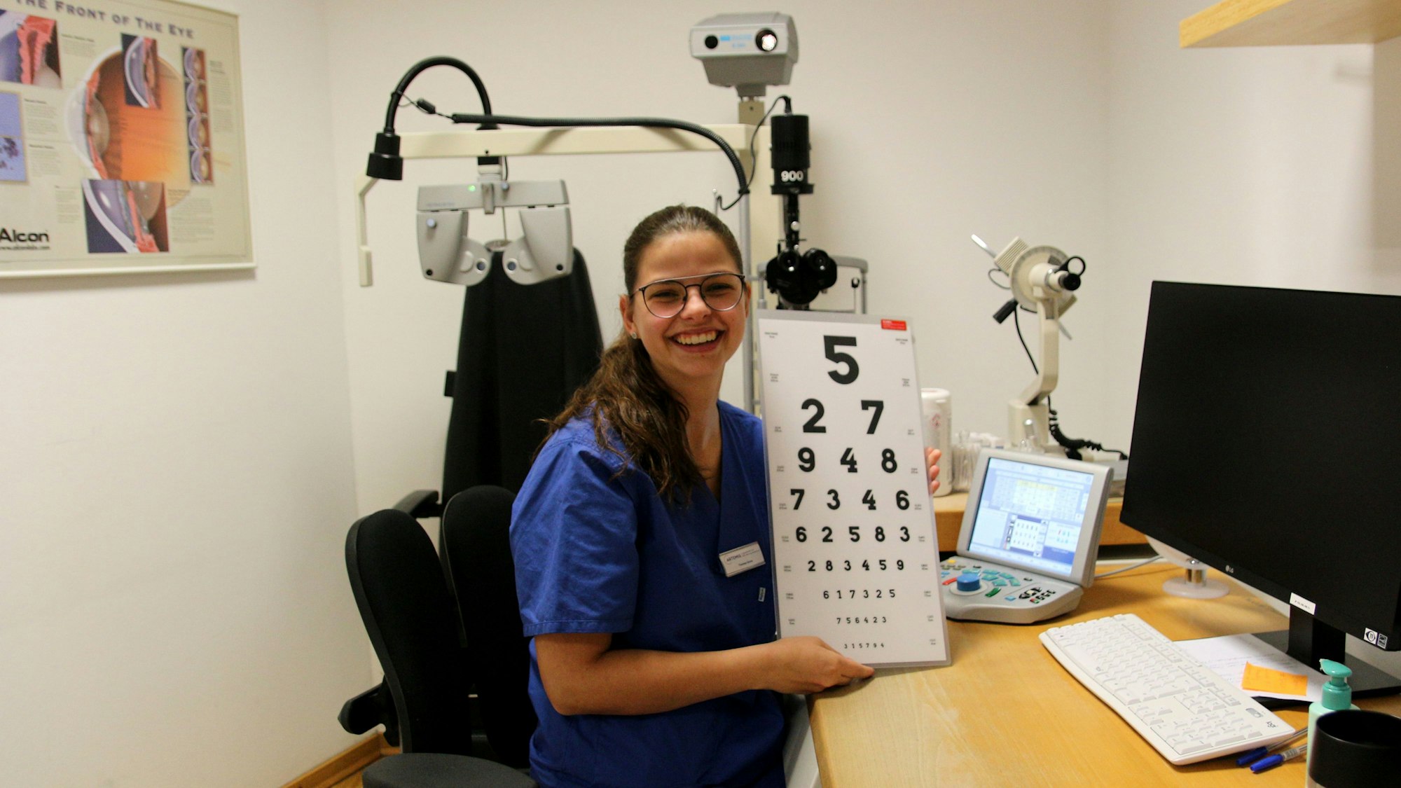 Eine junge Frau zeigt eine Tafel mit verschieden großen Zahlen.