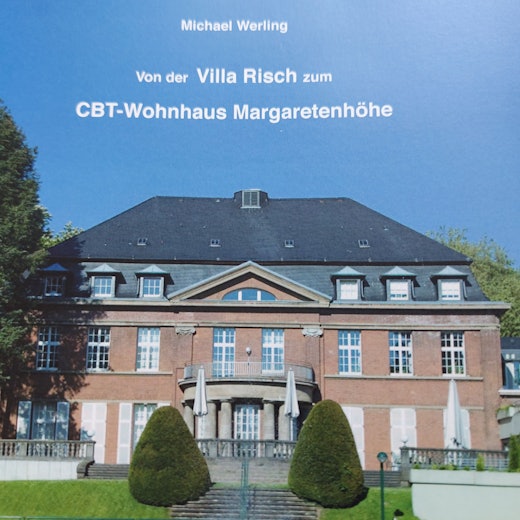 Villa Risch von der Gartenseite. Ein herrschaftlicher Bau mit Walmdach und großer Terrasse.