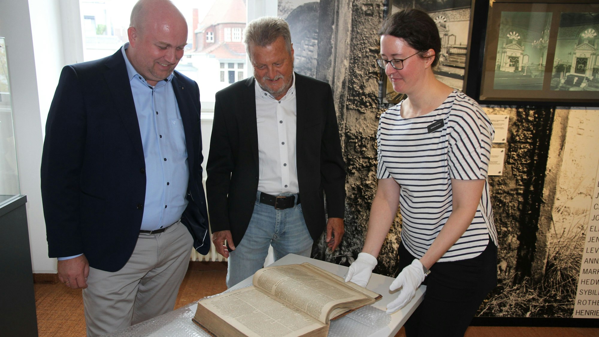 Zwei Männer und eine Frau mit einem historischen Buch